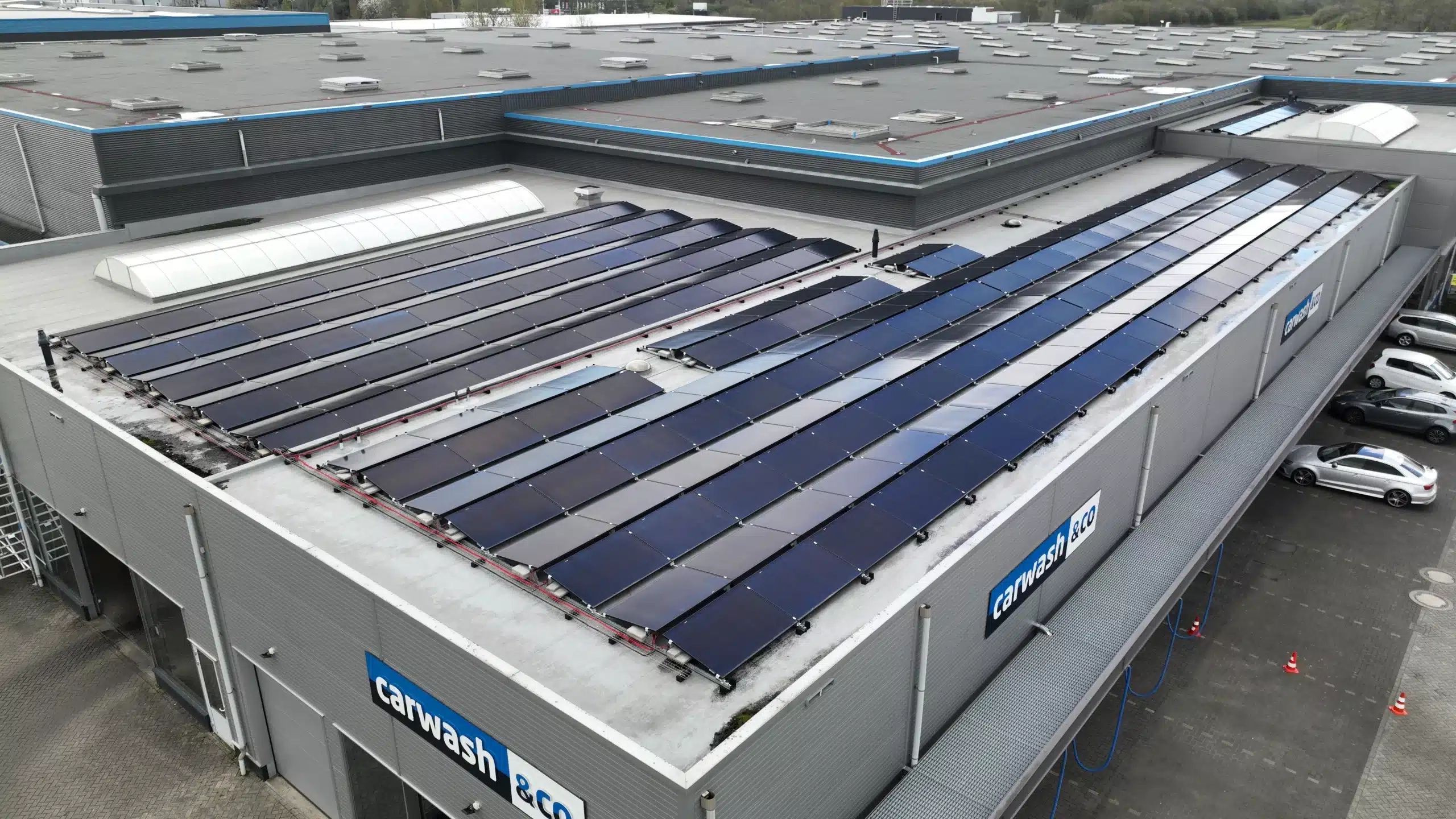 Luchtfoto van een zonnepanelen installatie met een groot aantal zonnepanelen op het dak, wat het gebruik van hernieuwbare energie door bedrijven toont. Zonnepanelen voor bedrijven.